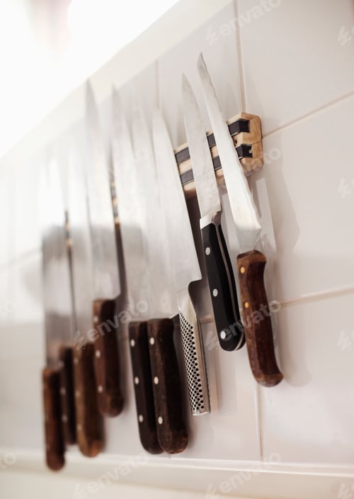 Preview: Close-up of various knives on tiled wall in restaurant kitchen