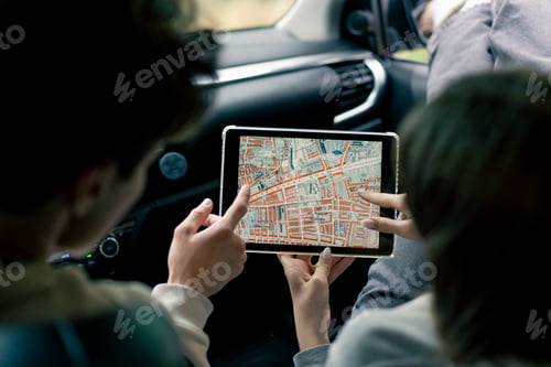Preview: A couple in a car conferring and planning the best route through the forest using a map on a tablet