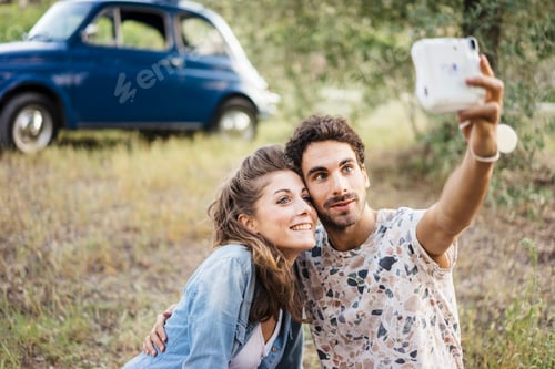 Preview: Romantic couple taking a selfie with a vintage camera in Tuscany country