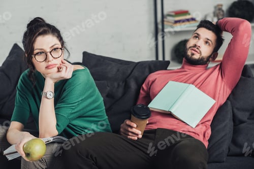 Preview: bored woman in glasses holding apple and sitting near handsome man with paper cup