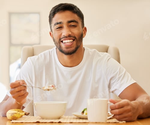Preview: Shot of a handsome young man sitting alone and having breakfast at home