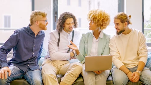 Preview: Woman talking to colleagues using laptop sitting in a coworking