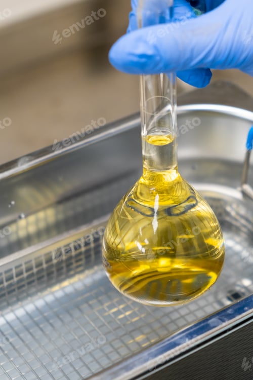 Preview: Scientist in blue rubber puts a yellow solution in the flask for dissolving or extraction into