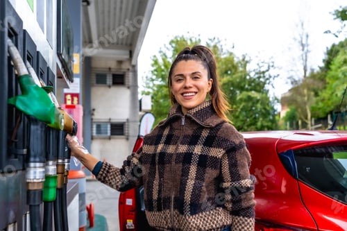 Preview: Woman smiling while refueling car at gas station