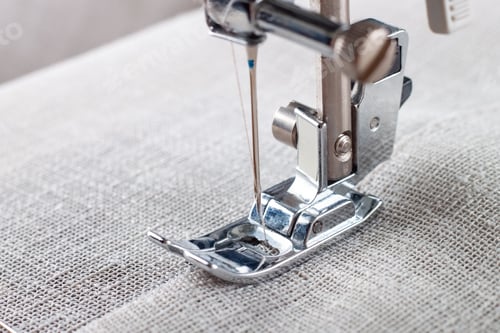 Preview: Modern sewing machine presser foot with linen fabric and thread, closeup