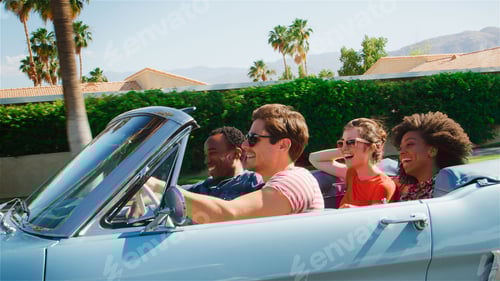 Preview: Side View Of Group Of Young Friends On Road Trip Driving In Classic Convertible Car