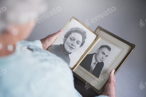 Preview: Cropped shot of a senior woman looking at old black and white photos of a man and a woman
