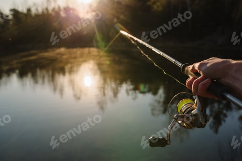 Preview: Fisherman with rod, spinning reel on the river bank. Sunrise. Fishing for pike, perch, carp. Fog aga