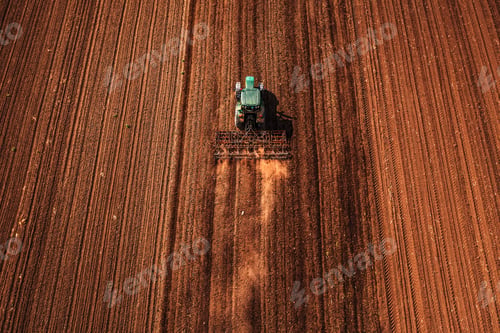 Preview: Agricultural tractor with tiller attached performing field tillage before the sowing season
