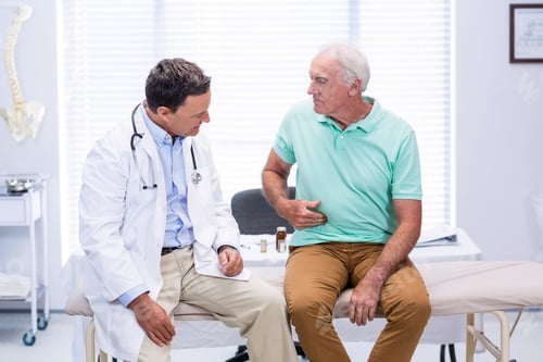 Preview: Senior man showing stomach ache pain to doctor