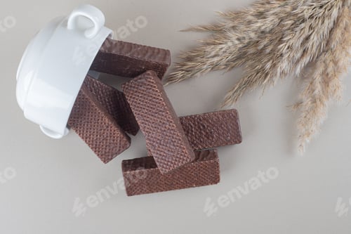 Preview: Bowl of chocolate wafers and feather grass stalks spilled over on marble background
