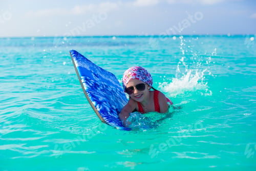 Preview: Little girl swimming on surfboard in the turquoise sea