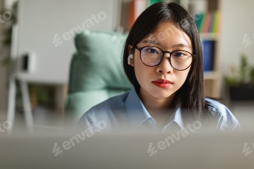 Preview: Japanese Business Female Wearing Earbuds Using Computer At Workplace Indoor