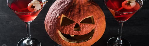 Preview: panoramic shot of spooky Halloween pumpkin and red cocktails on black background