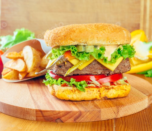 Preview: Juicy burger with fresh vegetables and crispy potatoes on a wooden board in a cozy setting