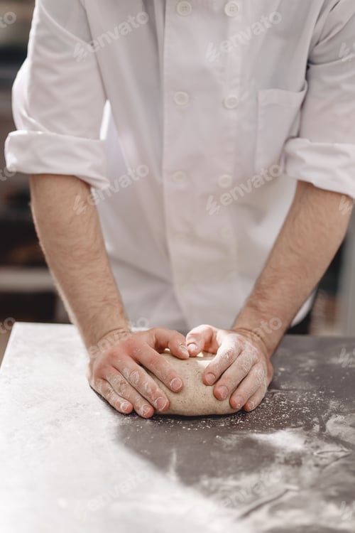 Preview: Baker kneads dough on the table in the bakery