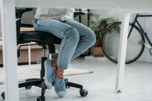 Preview: cropped view of woman in jeans and sneakers sitting on chair