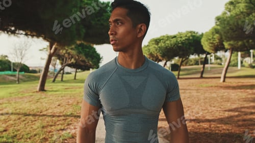 Preview: Guy in sportswear, an athlete walks along a path in a city park on a sunny day, a healthy lifestyle