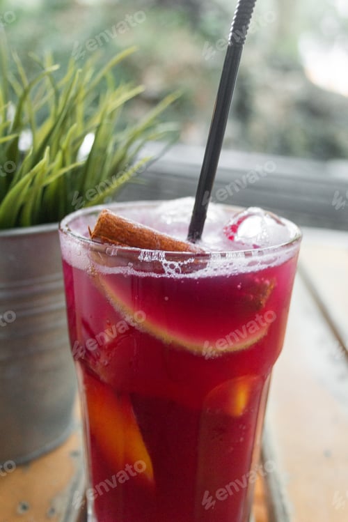 Preview: Misted glass of famous Portuguese red sangria with cinnamon stick, fruit and drinking straw