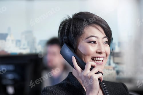 Preview: Smiling woman in office talking on phone