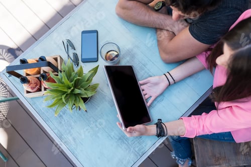 Preview: Top view of people with gadgets on a table outside