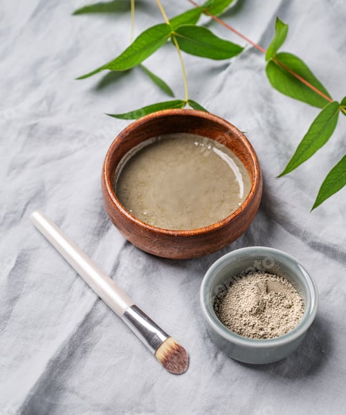 Preview: Organic cosmetic with blue clay, brush and branch on a linen background.