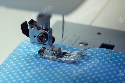 Preview: Macro shot of sewing machine steel pressure foot with needle and thread making stitches on blue