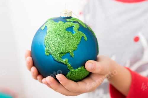 Preview: Close-up of little girl holding in hands Xmas glass bauble decoration ornament globe planet earth