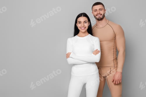 Preview: Man and woman in warm thermal underwear on grey background. Space for text