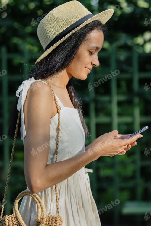 Preview: young African American woman in white dress is chatting on smartphone. adorable female model.