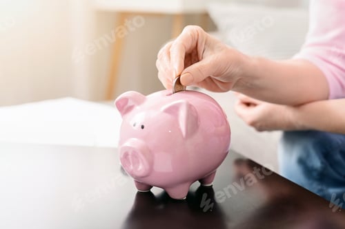 Preview: Woman Putting a Coin Into a Pink Piggy Bank