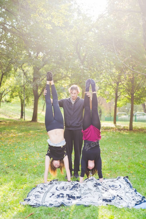 Preview: Man teaching two young girls how to handstand outdoor
