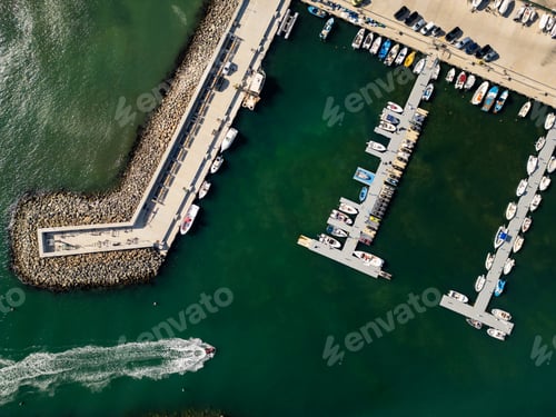 Preview: Aerial view of a busy marina with various boats docked along the pier near the coastline on a bright