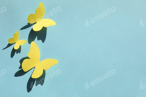 Preview: Yellow paper butterflies on turquoise background, top view. Space for text