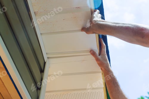 Preview: Installing vinyl soffit plastic panels on facade ceiling of a new home by an employee