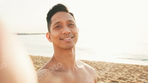 Preview: Close up of guy, an athlete with a naked torso standing on the beach makes a selfie on a smartphone