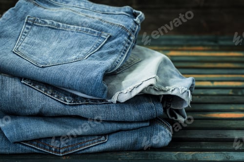 Preview: bunch of jeans on wooden background, fashionable clothes