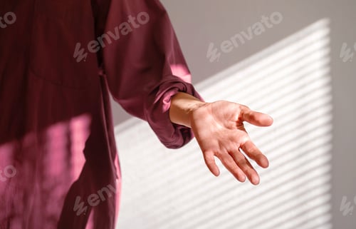Preview: Person Reaching Out Hand in Dappled Shadow of Window Blind on Wall. Offer Help or Assistance.