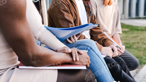 Preview: Hands of a group of friends sitting with notes in their hands outdoors
