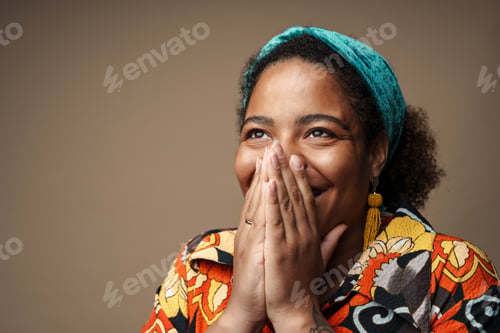Preview: Young black woman in headband smiling and covering her mouth
