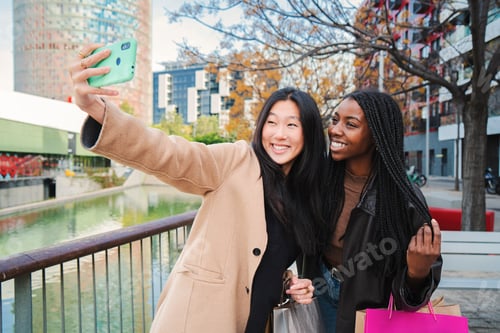 Preview: A couple of multiracial happy girls having fun takng a photo with a cellphone. Two young women