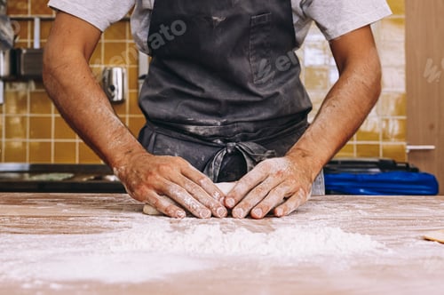 Preview: Anonymous man cook shaping dough in bakery