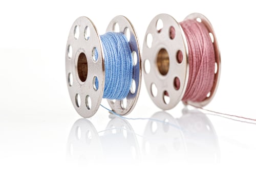 Preview: spools of blue and pink thread on a white background
