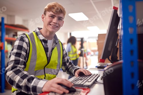 Preview: Portrait Of Male Intern Working In Busy Modern Warehouse On Computer Terminal
