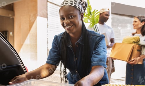 Preview: Cheerful african american woman packing stuff to auto trunk
