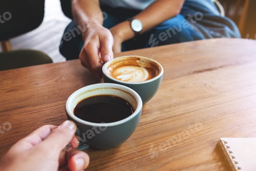 Preview: Closeup image of a woman and a man clinking coffee cups together in cafe