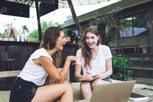 Preview: Female students laughing in street cafe