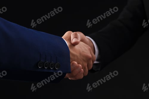 Preview: Business partners shaking hands on black background, closeup