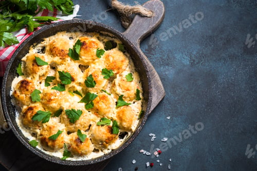 Preview: Meatballs in cream sauce on dark stone table top view.