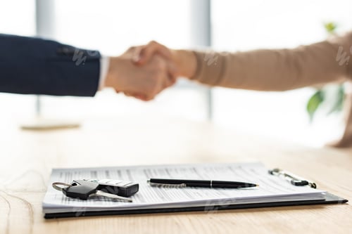 Preview: selective focus of clipboard, pen and car key near men shaking hands